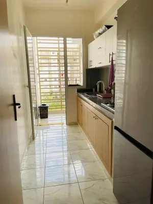 a kitchen with white cabinets and a large window at Appartement cosy avec vue jardin à Casablanca ! in Casablanca