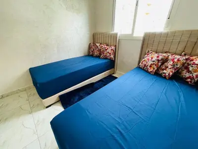 two beds in a room with blue sheets and pillows at Appartement cosy avec vue jardin à Casablanca ! in Casablanca
