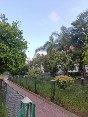 a green bench on a sidewalk next to a fence at Logement tout confort, équipé ! in Casablanca