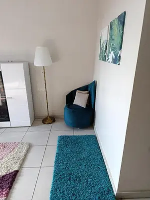 a living room with a blue chair and a blue rug at Logement tout confort, équipé ! in Casablanca