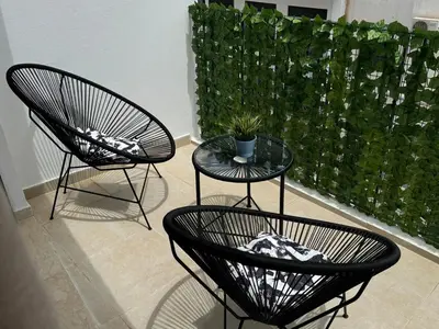 two black chairs and a table with a potted plant at Beautiful apartment with a terrace in Casablanca