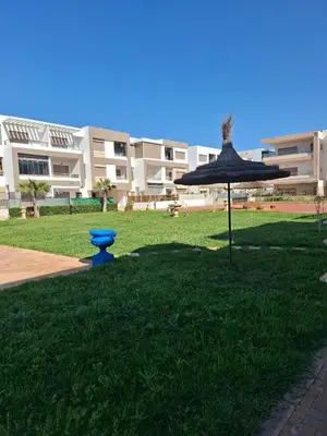 a umbrella in the grass in front of a building at Malaga el Mansouria valence in Casablanca