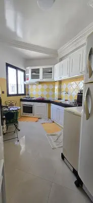 a kitchen with white cabinets and a table in it at La corniche in Casablanca