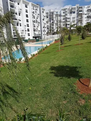a large apartment building with a swimming pool next to a park at Luxury apartment in Hay Riad, Prestigia, Rabat in Rabat