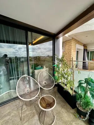 three chairs and tables on a balcony with windows at Domus Studio - Ambiance Zen au cœur de Casablanca in Casablanca