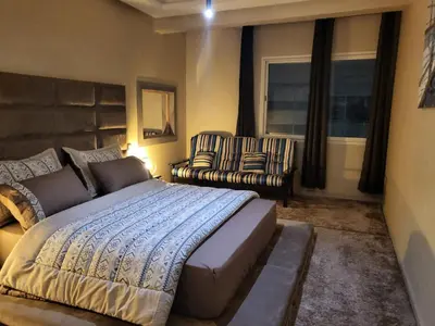 a bedroom with a bed and a couch and chairs at Cozy Appartement Relax in Mohammedia