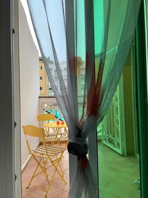 a view of a room with a table and a curtain at Al kawtar Vacation apartment in Mansouria in O Ben Slimane