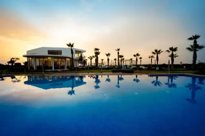 a large swimming pool in front of a building with palm trees at Garden Bay Signature AppartHotel in Casablanca