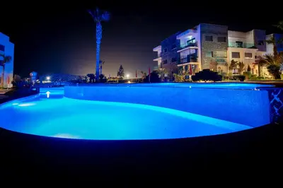 a large blue swimming pool at night at Garden Bay Signature AppartHotel in Casablanca