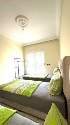 two beds in a room with green sheets at Charming home in Temara in Temara