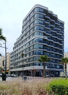 a tall building with palm trees in front of it at Studio de charme face corniche de Casablanca in Casablanca