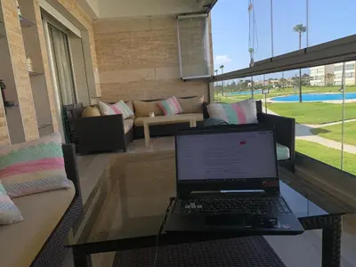 a laptop computer sitting on a glass table in a living room at Appartement avec Terrasse, Piscine & Plage à Ola Blanca 2 in Sidi Rahal