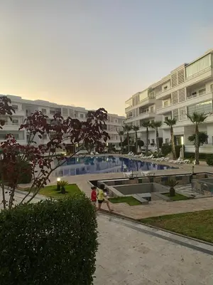 two people walking by a swimming pool in a building at Apartment in a residence in Pont Blondin