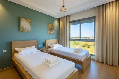two beds in a room with a large window at Chic, bright, 2 BR apartment, panoramic view in Temara