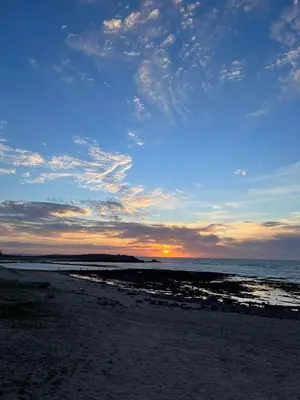 a beach with the sun setting in the distance at Superbe appartement en résidence avec piscine in Mohammedia