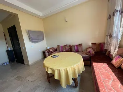 a living room with a table and a couch at Superbe appartement en résidence avec piscine in Mohammedia