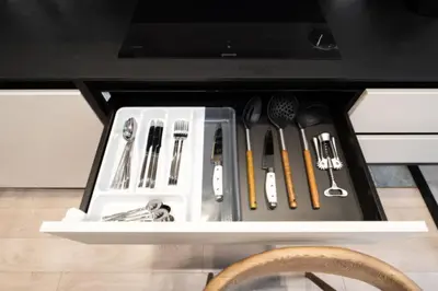 a drawer filled with cooking utensils on a shelf at charcho place in Les Camps