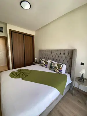 a bedroom with a large white bed with a headboard at Natura Appartement Pool View by 7AV Hotels in Mohammedia