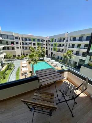 a balcony with two chairs and a table and a pool at Natura Appartement Pool View by 7AV Hotels in Mohammedia