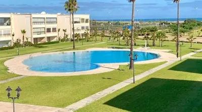 a swimming pool in a park with palm trees and a building at Studio Seaside Resort Casablanca in Dar Hamida