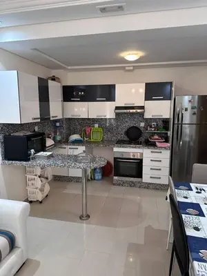 a kitchen with white cabinets and a table in it at Studio Seaside Resort Casablanca in Dar Hamida