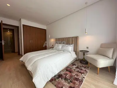a bedroom with a large white bed and a chair at Appartement Souissi avec 3 chambres in Rabat