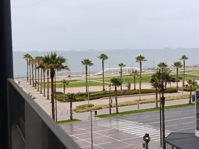 a view of a parking lot with palm trees and the ocean at Studio Luxe avec Vue sur la Corniche in Casablanca