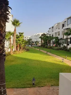 a green park with palm trees and buildings at Mansouria Beach Resort in Mohammedia