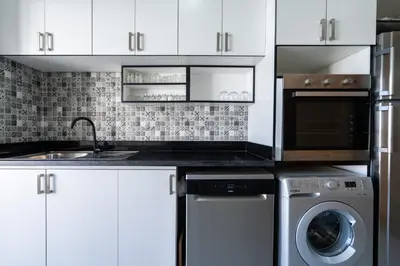 a kitchen with white cabinets and a washer and dryer at Luxury cozy apartment in Casablanca