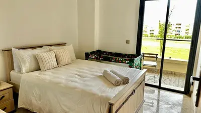a large white bed in a room with a window at Appartement avec piscine près de la mer in O Ben Slimane