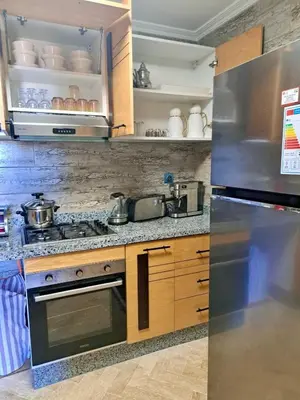 a kitchen with a stainless steel refrigerator and cabinets at Appartement avec piscine près de la mer in O Ben Slimane
