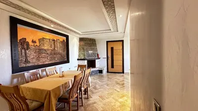 a dining room with a table and a painting on the wall at Appartement avec piscine près de la mer in O Ben Slimane