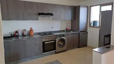 a kitchen with a stove and a washing machine at newly and fully furnished apprt in Sidi Rahal