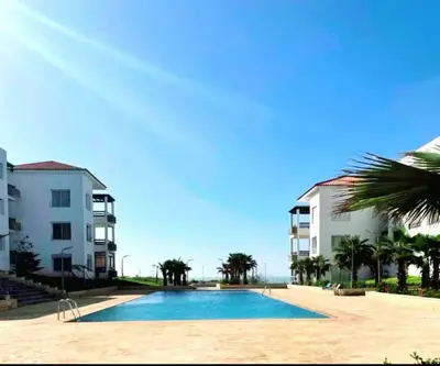 a swimming pool in front of two apartment buildings at appartement cité marine plage 5min in O Ben Slimane