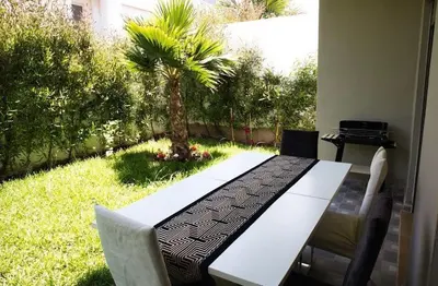 a white table and chairs in a yard with a palm tree at KST Home-Heaven Beach Sidi Rahal in Sidi Rahal