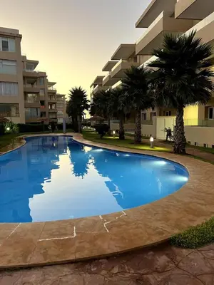a large blue swimming pool in front of a building at Appartement de luxe vue sur mer in Bouznika