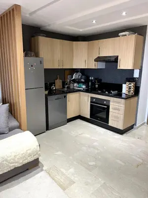 a kitchen with stainless steel appliances and wooden cabinets at Appartement de luxe vue sur mer in Bouznika