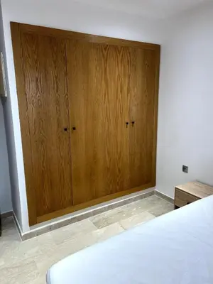 a bedroom with a large wooden cabinet next to a bed at Appartement de luxe vue sur mer in Bouznika