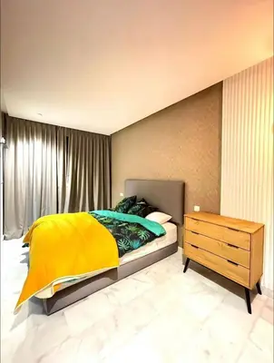a bedroom with a bed with a yellow blanket and a dresser at A102 Studio cosy & chic in Casablanca