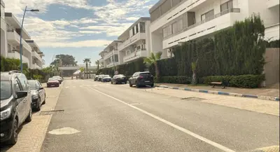 a street with cars parked on the side of a building at Marbella beach in Mansouria