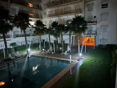 an image of a pool in a building with palm trees at Kettani Shems Bouznika in Bouznika