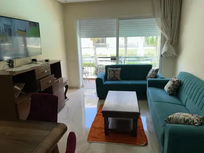 a living room with blue couches and a flat screen tv at Kettani Shems Bouznika in Bouznika