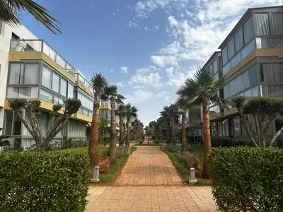 a brick pathway with palm trees in front of a building at Sidi Rahal Blue Beach in El Jadida