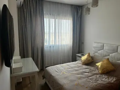 a bedroom with a bed with a window and a desk at Sidi Rahal Blue Beach in El Jadida