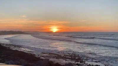 a sunset over a beach with the ocean at Sidi Rahal Blue Beach in El Jadida