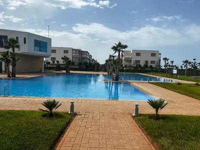 a large swimming pool with palm trees and buildings at Sidi Rahal Blue Beach in El Jadida