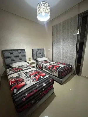a bedroom with two beds and a lamp at Maison à louer à Mohammedia in Mohammedia