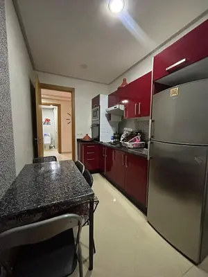 a kitchen with a table and a stainless steel refrigerator at Maison à louer à Mohammedia in Mohammedia