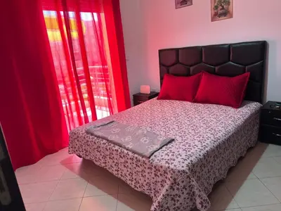 a bedroom with a large bed with red curtains at Beautiful 2 bedrooms apartment in Bouznika in Bouznika