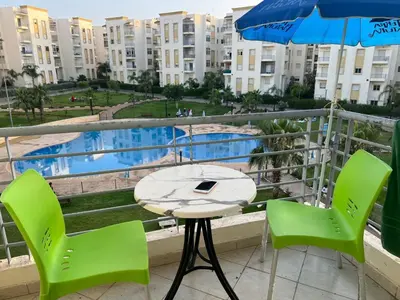 a table and chairs and an umbrella on a balcony at Beautiful 2 bedrooms apartment in Bouznika in Bouznika